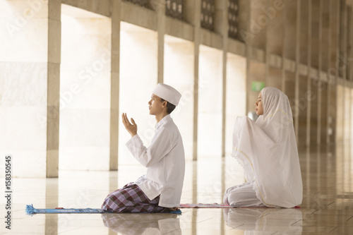 Man and woman praying in mosque © Creativa Images