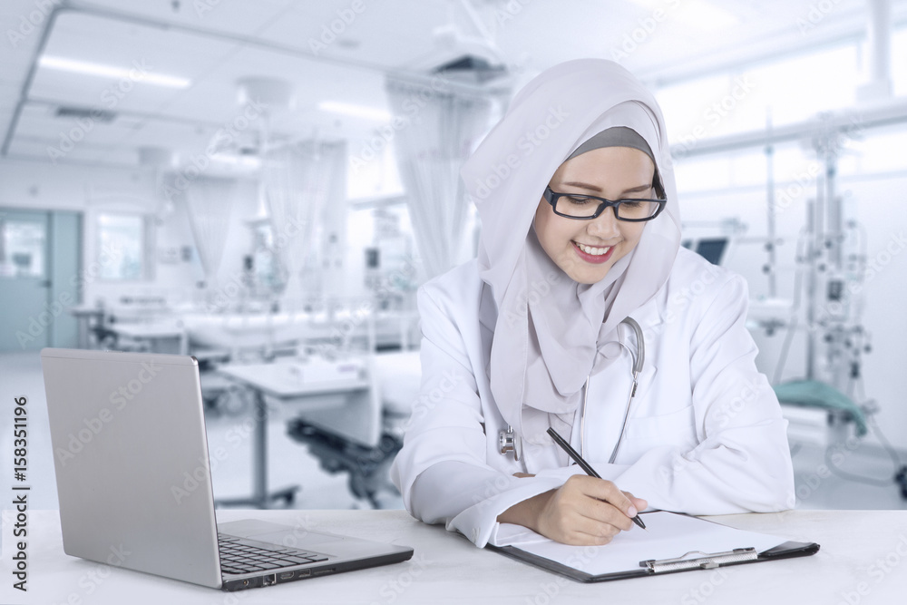 Muslim doctor writing report in hospital Muslim doctor writing report in hospital