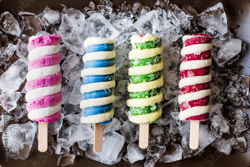 Popsicles ice cream with ice on dark surface.