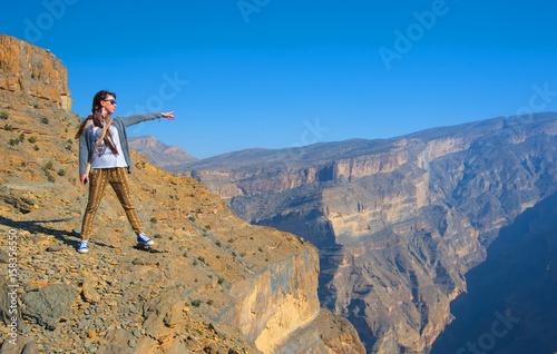 A girl stands on the mountain and admire the view of mountains, Grand canyon, Oman