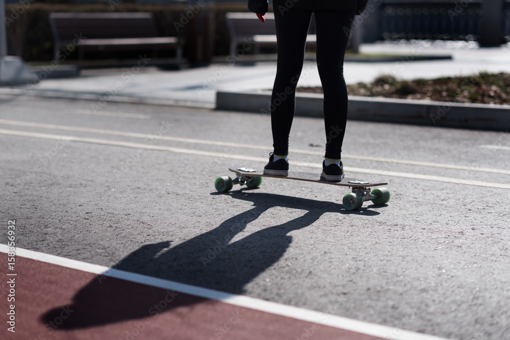 Young women is riding on a longboard in a black leggings Young women is riding on a longboard in a black leggings