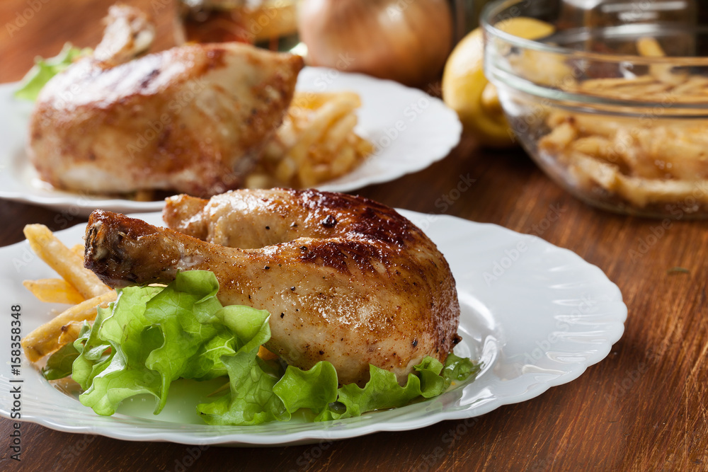 Roasted chicken legs with french fries and lettuce