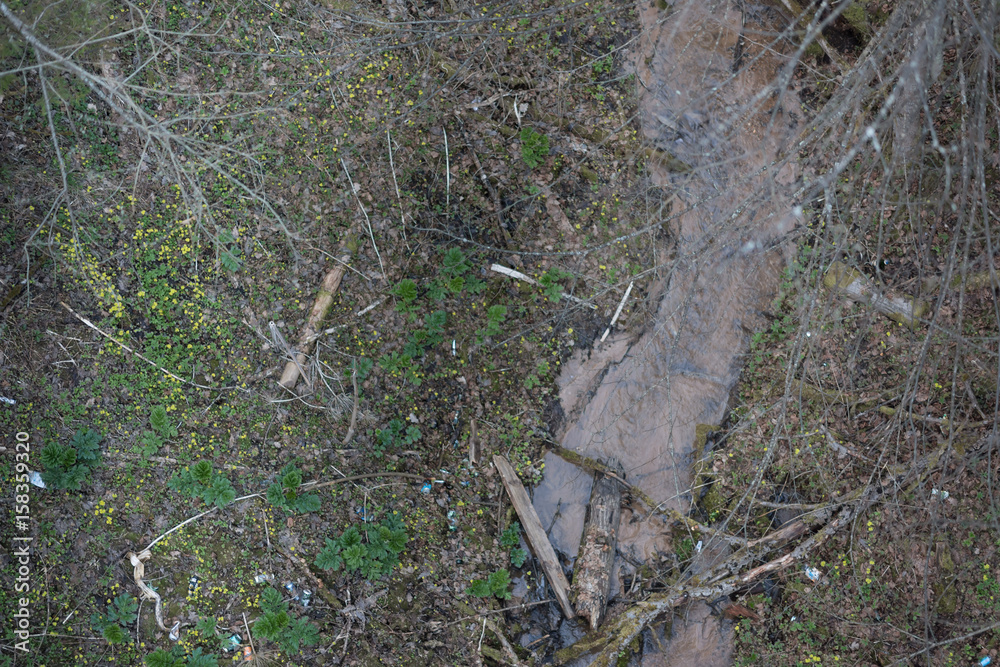 Damaged landscape of river bank with small river. Water polluted with mud due to landslide Damaged landscape of river bank with small river. Water polluted with mud due to landslide