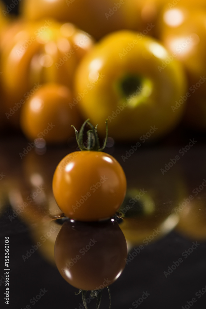 Yellow tomatoes on black background ,water drops , mirror Yellow tomatoes on black background ,water drops , mirror