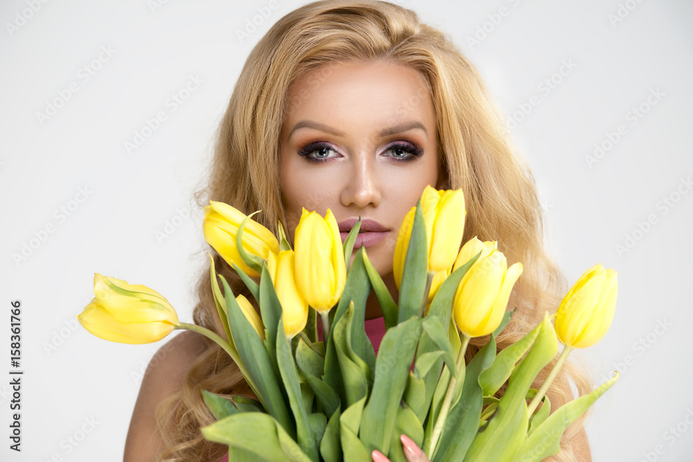 Beautiful blonde girl in pink dress with yellow flowers tulips in hands Beautiful blonde girl in pink dress with yellow flowers tulips in hands