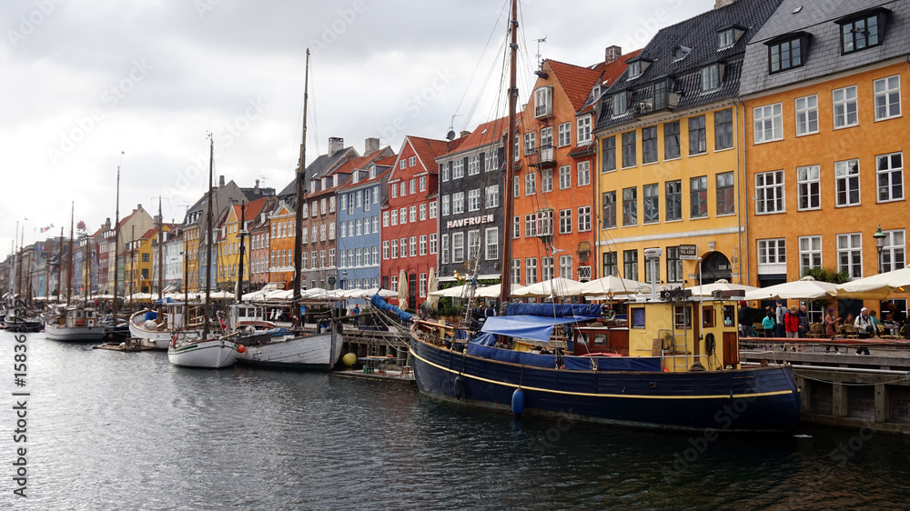 COPENHAGEN, DENMARK - MAY 31, 2017: people in open cafes of the famous Nyhavn promenade. Nyhavn a 17th century harbour in Copenhagen with typical colorful houses and water canals, Copenhagen, Denmark
