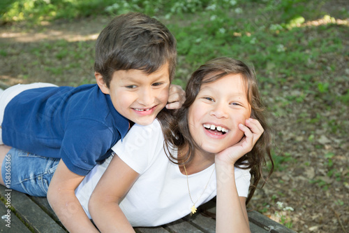 young brother and a young sister play together in the garden grass © OceanProd