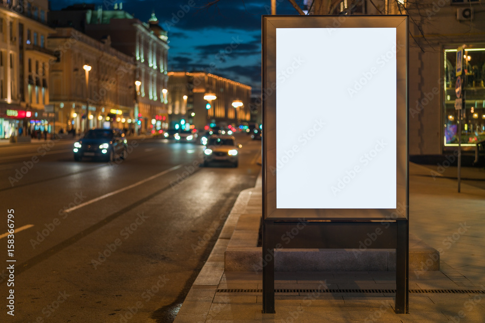 Vertical blank glowing billboard on night city street. In background buildings and road with cars. Mock up. Vertical blank glowing billboard on night city street. In background buildings and road with cars. Mock up.