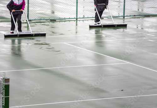 Workers remove water from the tennis court.