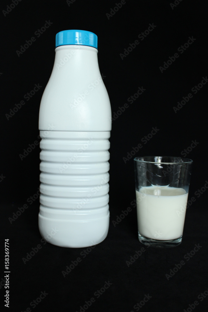 une bouteille de lait avec un verre rempli de lait sur fond noir une bouteille de lait avec un verre rempli de lait sur fond noir