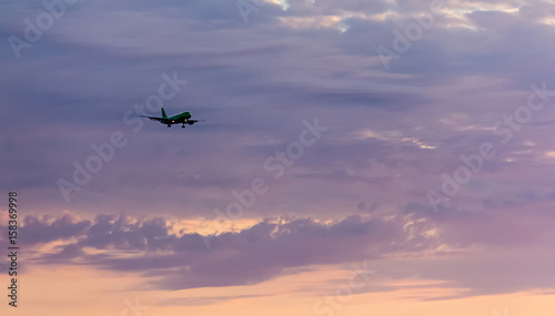 passenger plane flies high in the sky in the rays of the sunset goes on landing