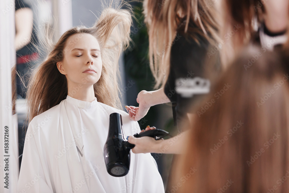 Hairdresser dries hair with hairdryer in beauty salon Hairdresser dries hair with hairdryer in beauty salon