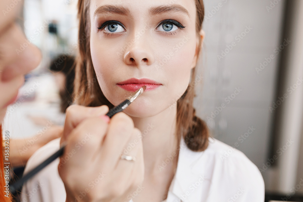 Closeup of female makeup artist paint her lips by cosmetic brush lipstick Closeup of female makeup artist paint her lips by cosmetic brush lipstick