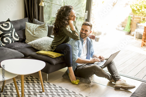 Portrait of a smiling young couple using laptop at home indoor