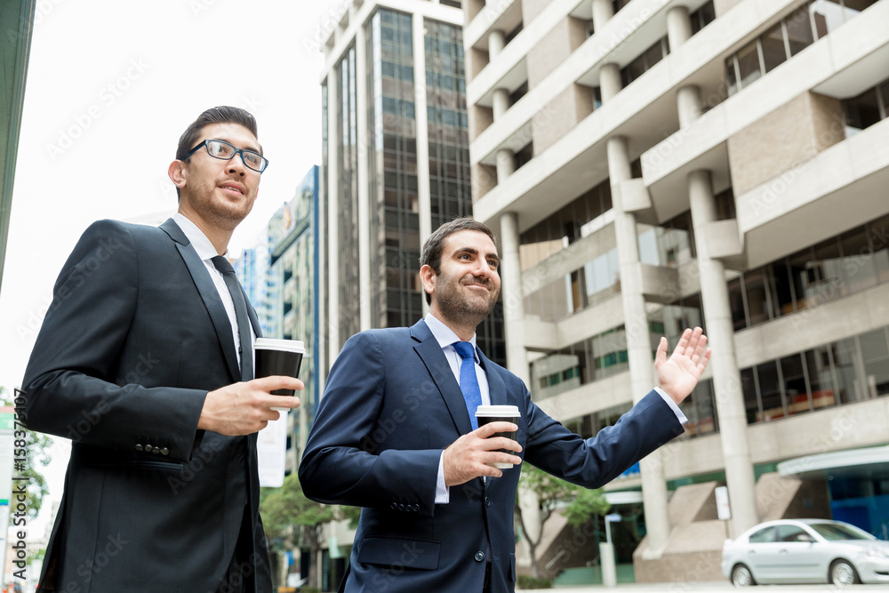 Two young businessmen hailing for a taxi