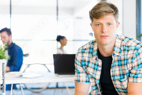 Young man sitting and looking at camera in office © Sergey Nivens