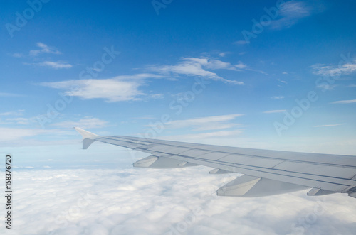 Wing of airplane flying above the cloud