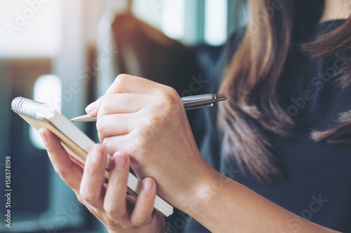 Closeup image of a woman writing and taking note on notebook in office