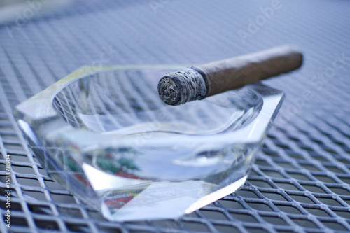 Close up of cigar with glass ashtray on the wired table photo