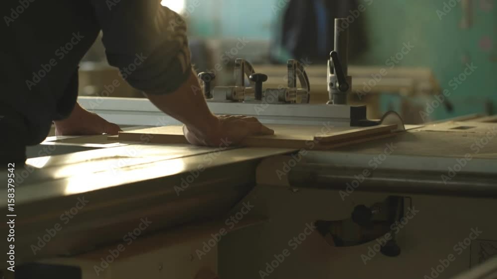 Man carpenter mills the piece of wood by a grinding machine in his home workshop Man carpenter mills the piece of wood by a grinding machine in his home workshop