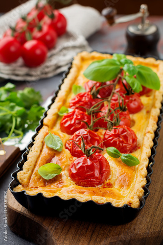 Cherry tomatoes and cheese tart on a dark background. Selective focus.Top view.