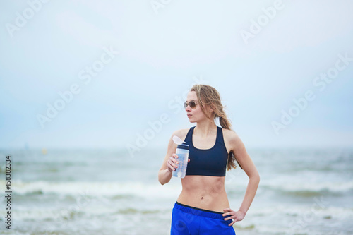 Runner girl drinking water from on running break
