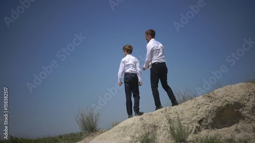 Happy father and son throw stones into the water while standing on a cliff, playing with a baby in the open air,