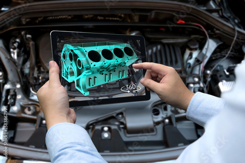 Augmented reality technology and engineering marketing concept. Hand holding tablet with AR service application to rotate 3d rendering of energy block 360 degrees with blur car engine room background