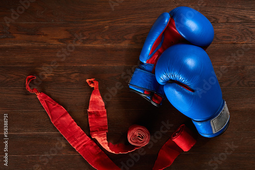 Top view of blue and red boxing gloves and bandage on wooden plank background. photo