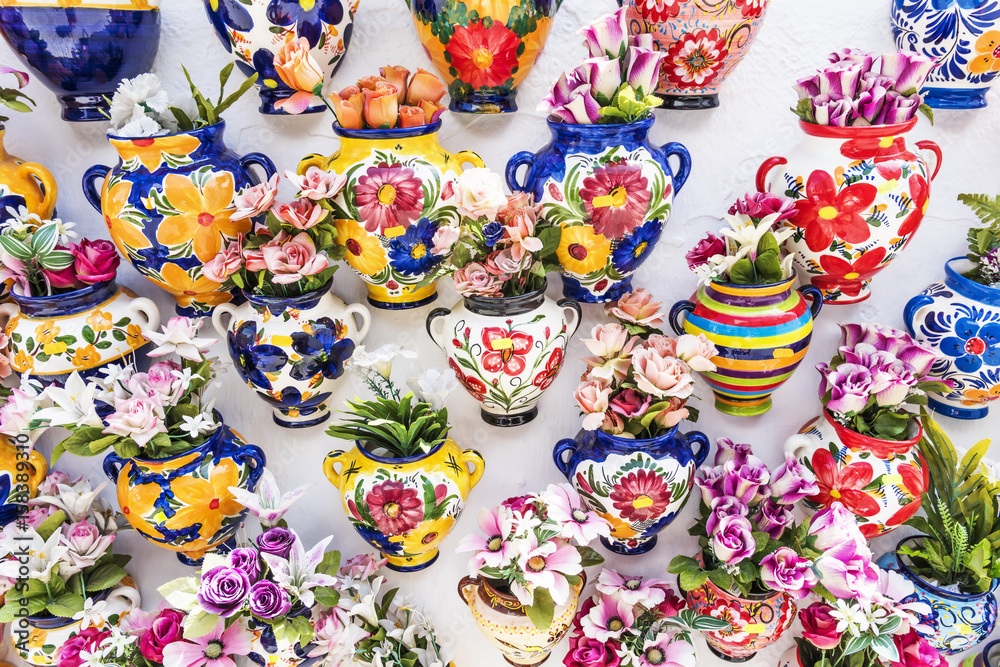 Colourful ceramic vases with flowers on a shop wall at Mijas