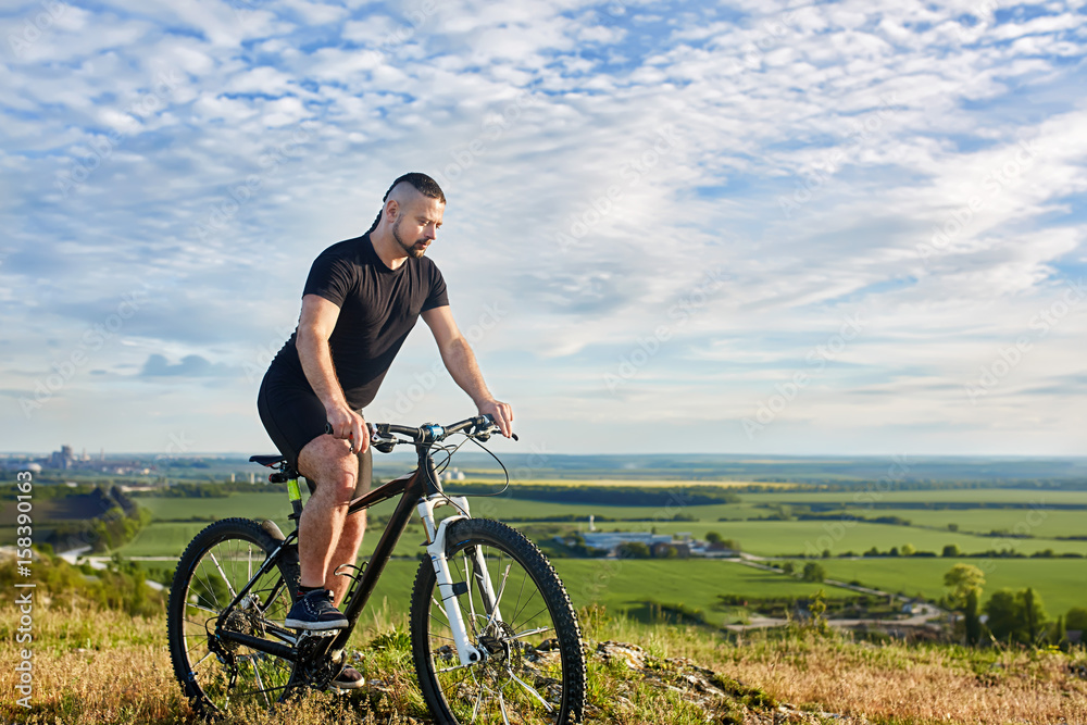 Attractive cyclist riding the bike on the beautiful summer mountain tril.