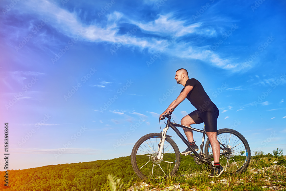 Young cyclist riding the bike on the beautiful summer mountain trail.