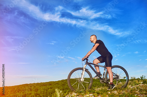 Fototapeta Naklejka Na Ścianę i Meble -  Young cyclist riding the bike on the beautiful summer mountain trail.