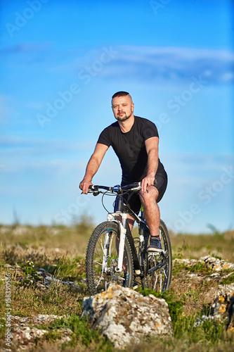 Young athlete cyclist riding mountain bike on rocky trail in the countryside.