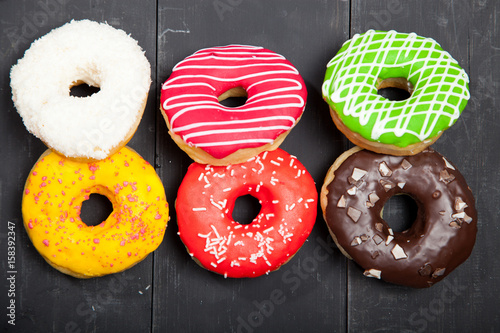 Colorful donuts on a black wooden background