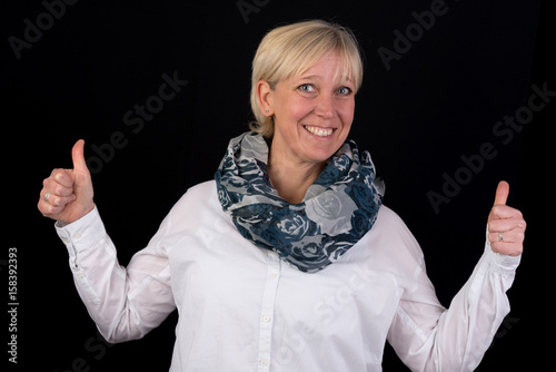 attractive blonde mature woman giving thumbs-up as positive signal - photograph on black background