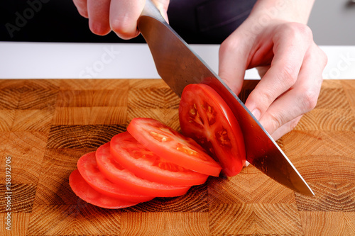 Woman cutting fresh red tomatoes on wooden board ingredients for salad