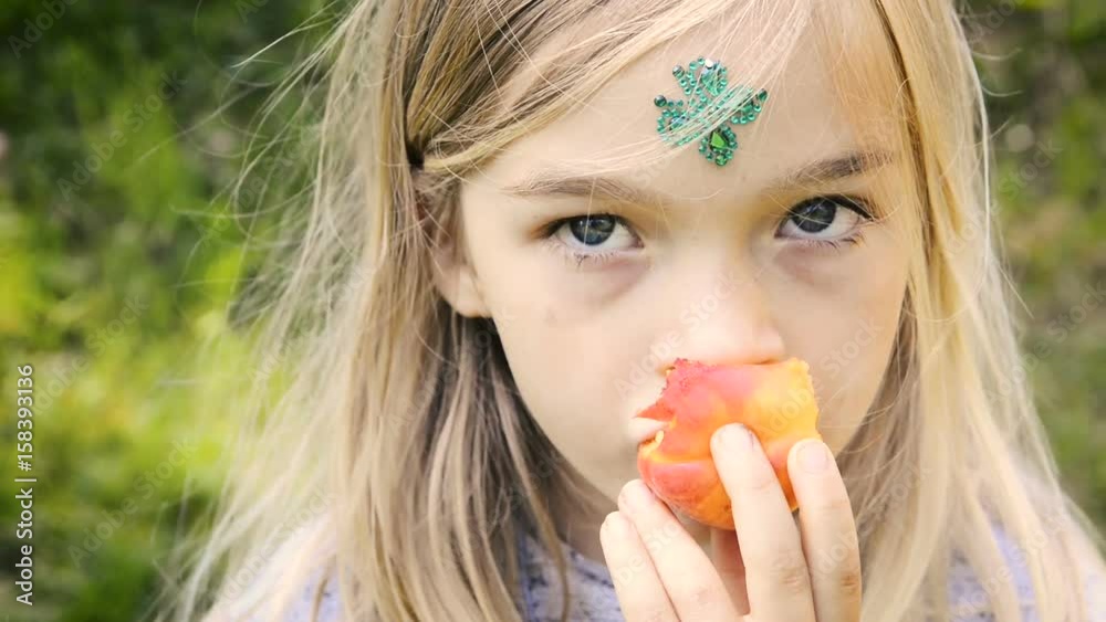 Child blond girl eating apricot outdoors in the garden Child blond girl eating apricot outdoors in the garden