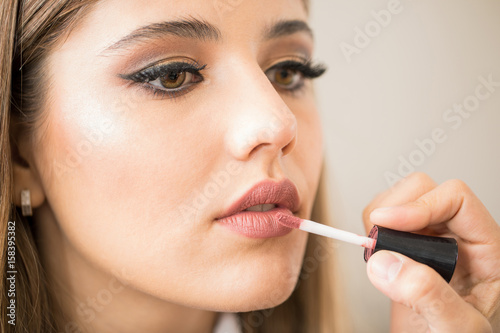 Woman getting lipstick on her lips
