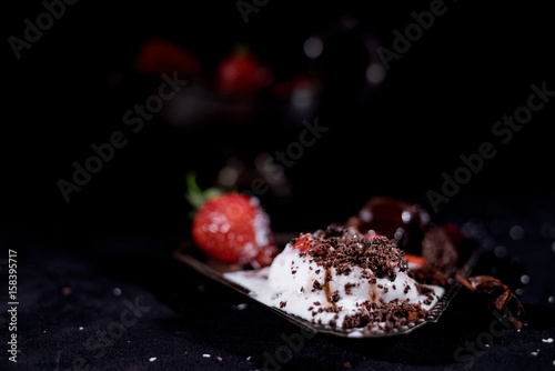 White icecream with chocolate and strawberry on the black background