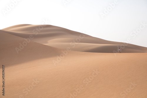 Beautiful woman hiking on giant sand dunes.