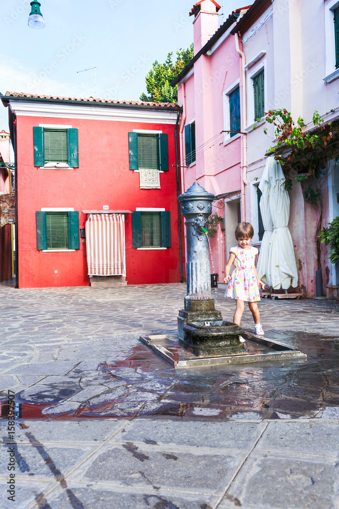 Obraz premium The girl washes hands in fountain. The first acquaintance with fountains of island of Burano