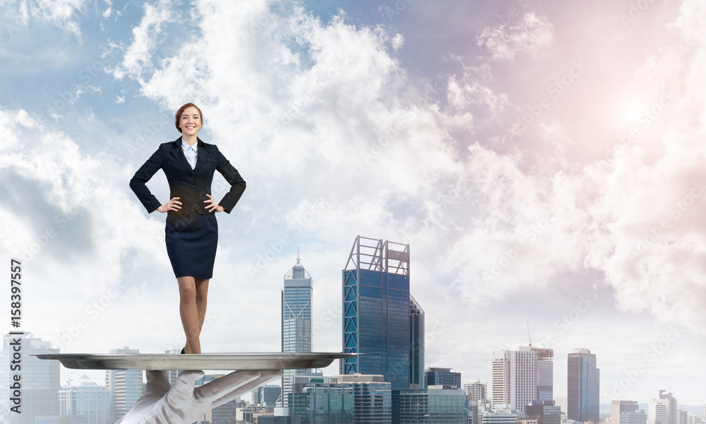 Confident elegant businesswoman presented on metal tray against cityscape background Confident elegant businesswoman presented on metal tray against cityscape background