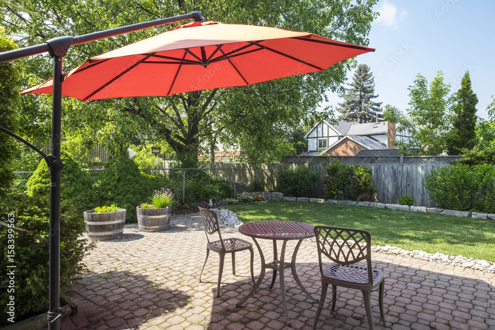 Obraz premium Backyard Garden with Bright Orange Cantilever Umbrella and Bistro Set