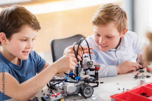 Interested smiling male children creating toy