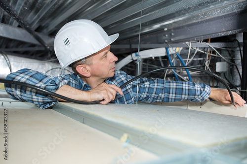 Electrician installing cables into confined space photo