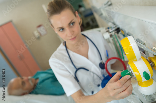 Nurse adjusting equipment in patient's room