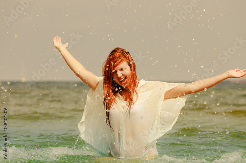 Redhead woman playing in water during summertime