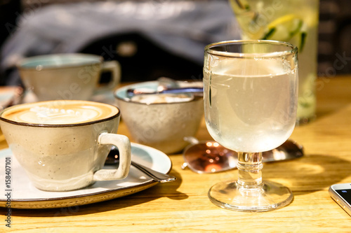 Fototapeta Naklejka Na Ścianę i Meble -  A Cup of coffee and a glass of water or lemonade stand on the table.