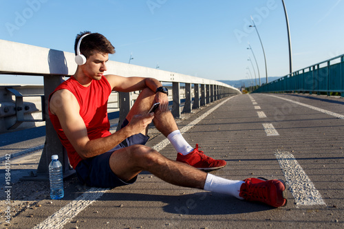 Portrait of young athlete man using mobile phone.